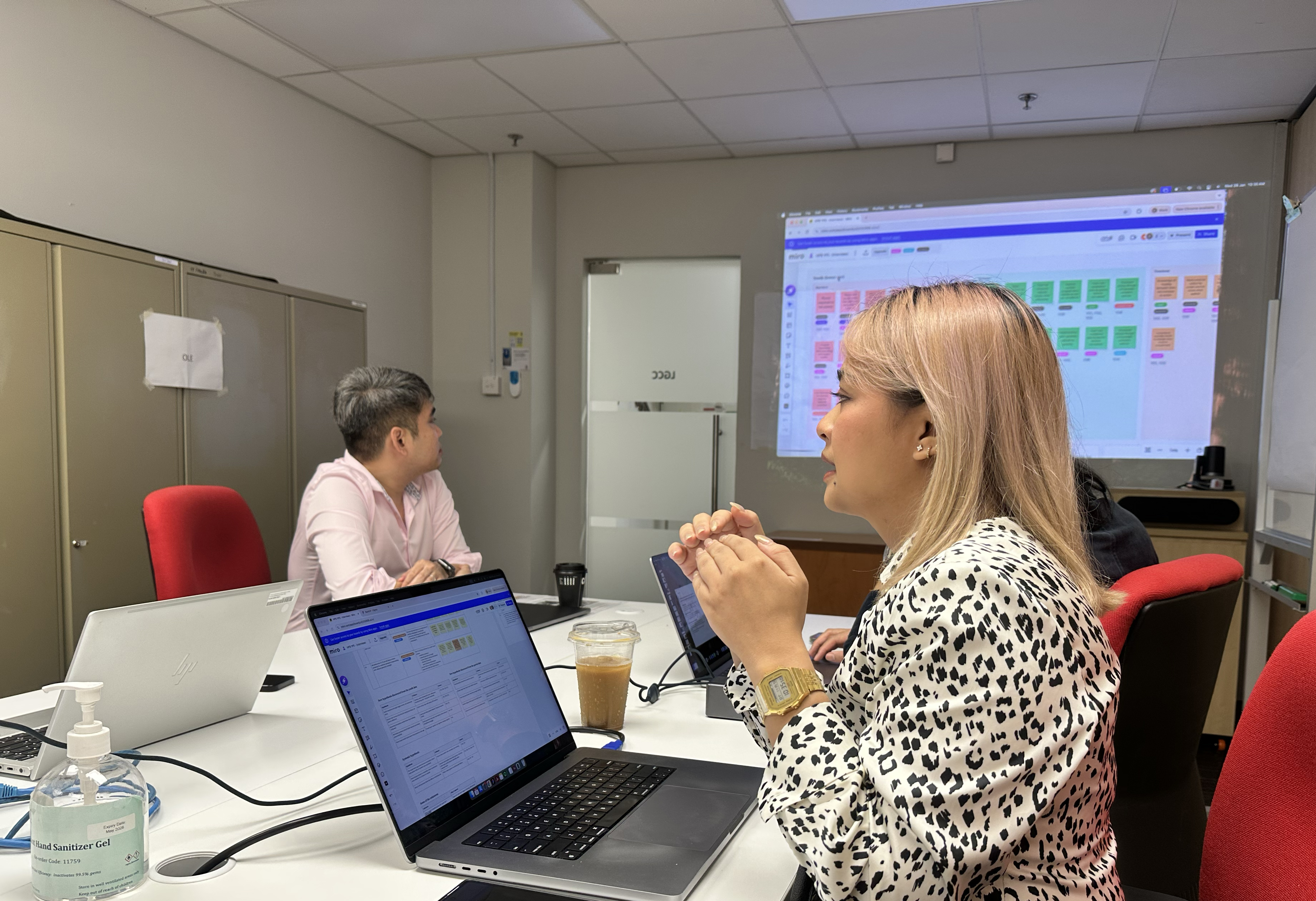 Research synthesis session — two team members reviewing behavioural data on projected board